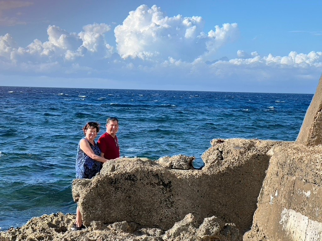 Two people standing on a rock with ocean view